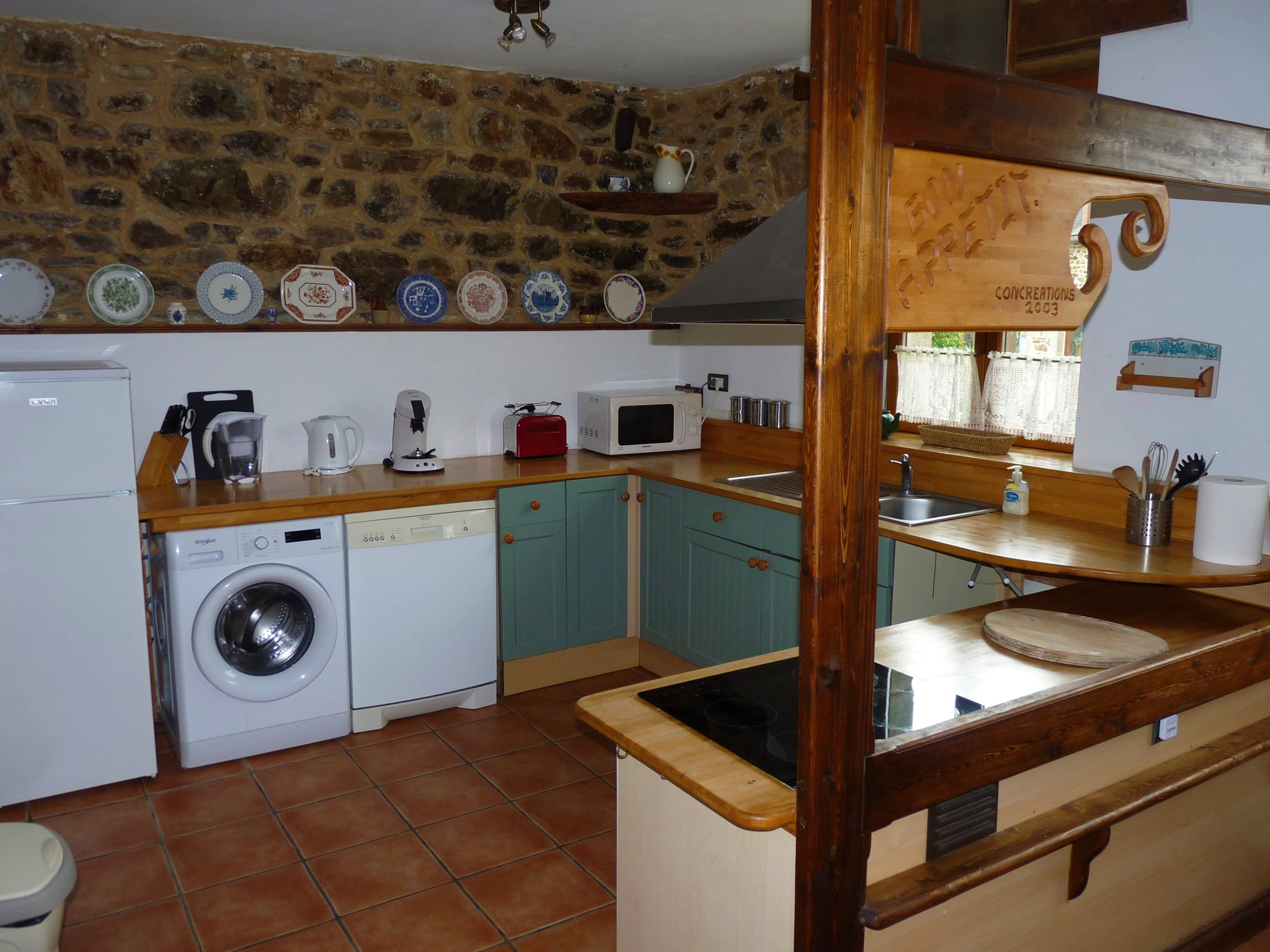 Kitchen of La Julerie cottage in Brittany, France, with a dining table, high-end appliances, and a view of the garden. Ideal for preparing holiday meals with family or friends.
